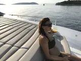 Guest in bathing suit sitting on cushioned seat enjoying a beverage on Mowana Yacht