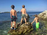 Three young guests playing on the rocks awaiting Mowana Yacht to arrive